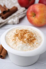 Delicious rice pudding with cinnamon and apples on white table, closeup