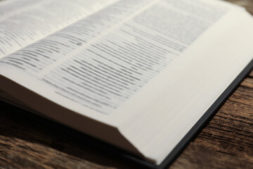 Open Holy Bible in English language on wooden table, closeup
