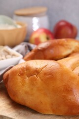 Delicious pirozhki (stuffed pastry pies) and ingredients on table, closeup