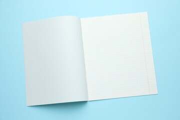 Open copybook on light blue background, top view