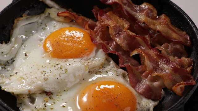 breakfast roasted bacon and two eggs on pan close up food rotation