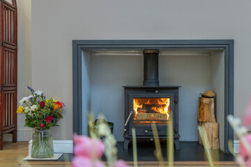 Cozy wood burner in a modern house. Minimalist real estate lifestyle photo of a fireplace with logs...