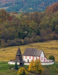 Picturesque autumn mountain landscape with hills, meadows and romantic historic wooden building at colorful sunset. The village of Cerin near Banska Bystrica, Slovakia