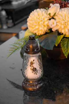 Candle and yellow chrysanthemums on the grave.