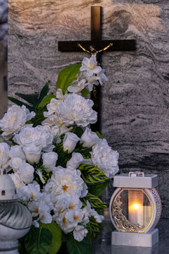 Elegant white flowers and a white candle on the grave.