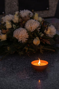 Candle and flowers on a grave at night.