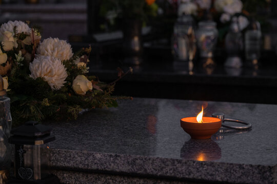 Candle and flowers on a grave at night.