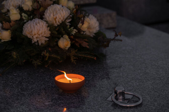 Candle and flowers on a grave at night.