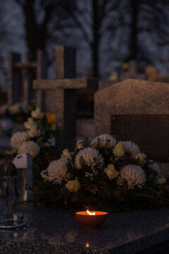 Candle and flowers on a grave at night.