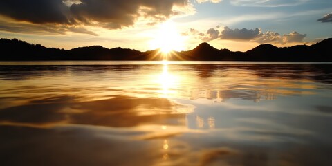 Fototapeta premium A sunset over a body of water with mountains in the background