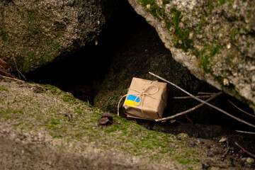A gift box and a Ukrainian flag lie under the ruins in the stones in Ukraine, help for Ukraine
