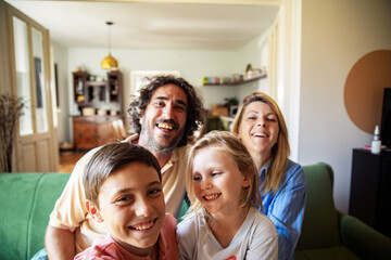 Selfie portrait of a happy family sitting together on a cozy living room couch