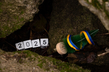 Christmas tree and Ukrainian flag ribbon and cubes with the date 2025 lie under rubble in Ukraine on Christmas in Ukraine, New Year