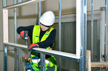 Construction worker mounting plasterboard on metal frame
