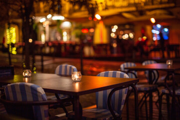 Empty table and chairs in an outdoor restaurant at night, blurred background