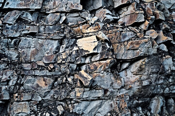 Frontal view of a natural rock wall made of granite stone.