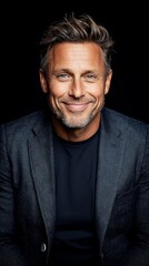 Obraz premium A man in a black shirt and a gray jacket smiles at the camera
