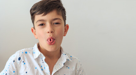 A young boy, aged 6-8, practicing speech therapy exercises. The photo highlights themes of speech correction, developmental support, and language learning. Copy space