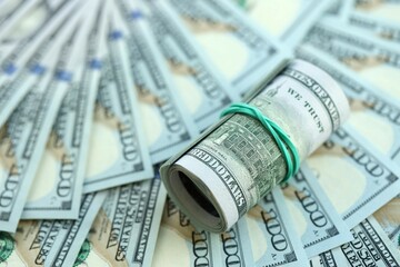 Roll of hundred dollar bills USD banknotes lies on big amount of united states money