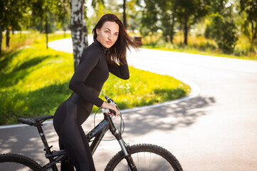 Caucasian woman riding a bike in a park. 