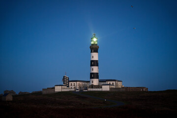 Stunning Night View of Phare du Créac'h Lighthouse Illuminating the Night Sky in Ouessant,...