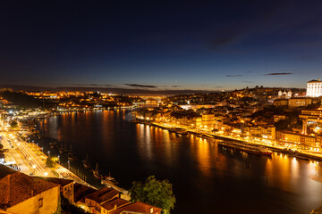 Fototapeta premium Stunning Night View of Porto's Riverside with Illuminated Buildings and Bridges Reflecting on Douro River, Portugal