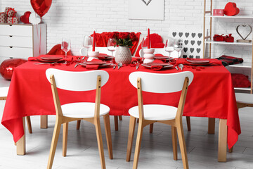 Festive table setting decorated for Valentine's Day with red roses and candles at home