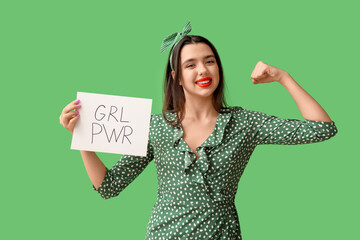 Beautiful young happy pin-up woman holding paper sheet with text GIRL POWER and showing muscles on...