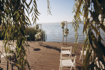 Wedding ceremony setup overlooking lake with white chairs and floral arrangements