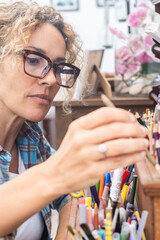 Woman painting on a large canvas in her art studio, working with brushes and vibrant colors, surrounded by artistic tools and fully focused on creating a professional and expressive artwork