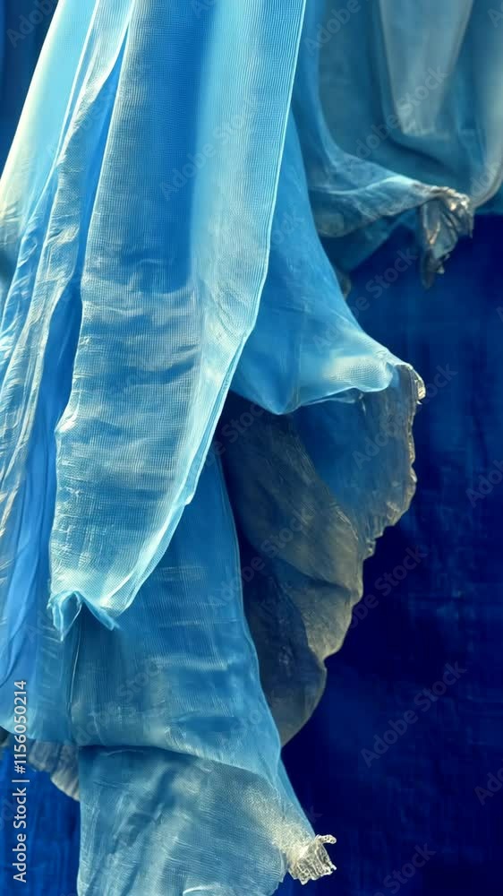 Poster soft blue fabrics gently draping against a textured blue background in a harmonious display of color