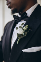 Groom wearing black suit with bow tie and white rose boutonniere