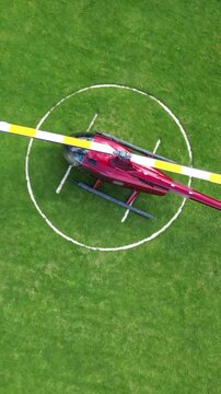 helicopter parked grass heliport vibrant red rotor blade unique perspective operational aspects circling downward aerial shot h pad drone aviation london scenic view travel air 