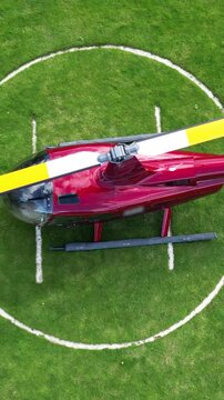 unique perspective red helicopter parked grass field heliport essence aviation operations london top down birdseye aerial shot view downward helipad scenic travel 