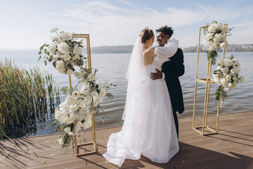Interracial couple getting married on a pier by a lake
