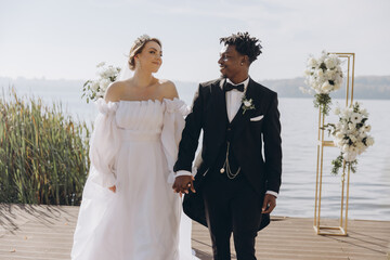 Interracial couple holding hands during wedding ceremony