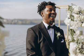 Groom laughing during wedding ceremony by the lake