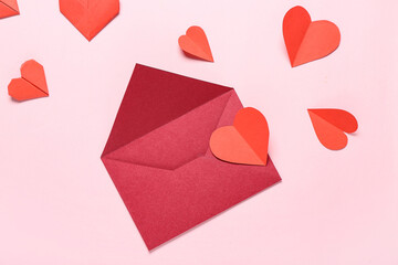 Composition with envelope and red paper hearts on pink background. Valentine's Day celebration