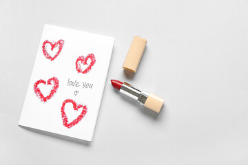 Fototapeta na wymiar Greeting card with text LOVE YOU and red lipstick on grey background. Valentine's Day celebration