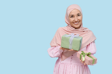 Mature Muslim woman with gift boxes on blue background. International Women's Day