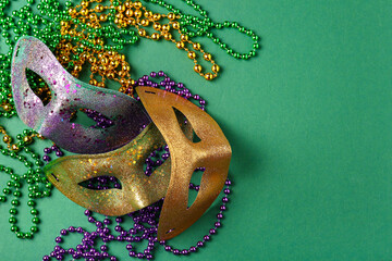 Shiny carnival masks with beads for Mardi Gras celebration on green background