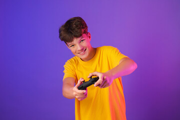 Happy teenage boy playing video game with controller on purple background © New Africa