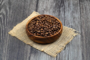 Wooden bowl with coffee beans on wooden background