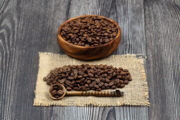Wooden bowl with coffee beans on wooden background