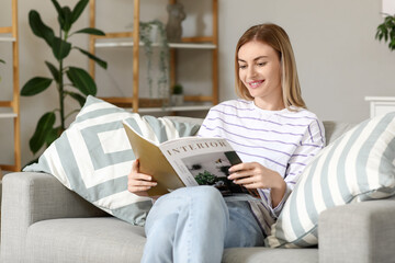 Young woman reading magazine on sofa at home
