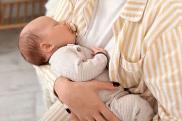 Mother holding cute little sleeping baby with pacifier on bed at home, closeup