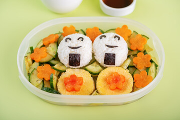 Bento box with onigiri with chicken filling and vegetables