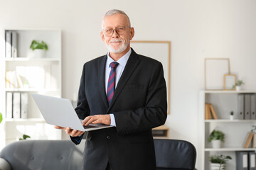 Portrait of senior businessman with laptop in office