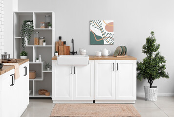 Shelving unit and kitchen counter with utensils near light wall in kitchen