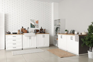 Shelving unit and kitchen counters with utensils near white brick wall